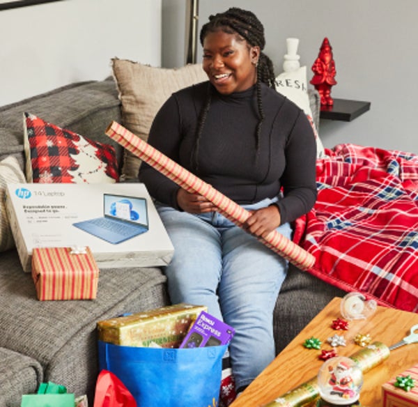 Elise sits on couch to wrap presents