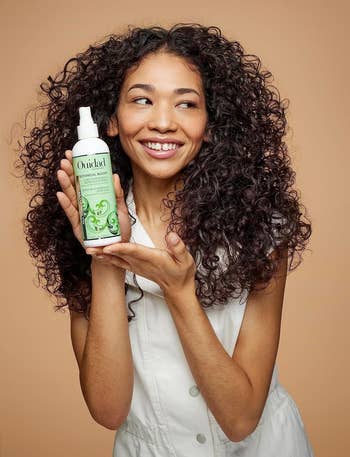 model holding a bottle of Ouidad hair product