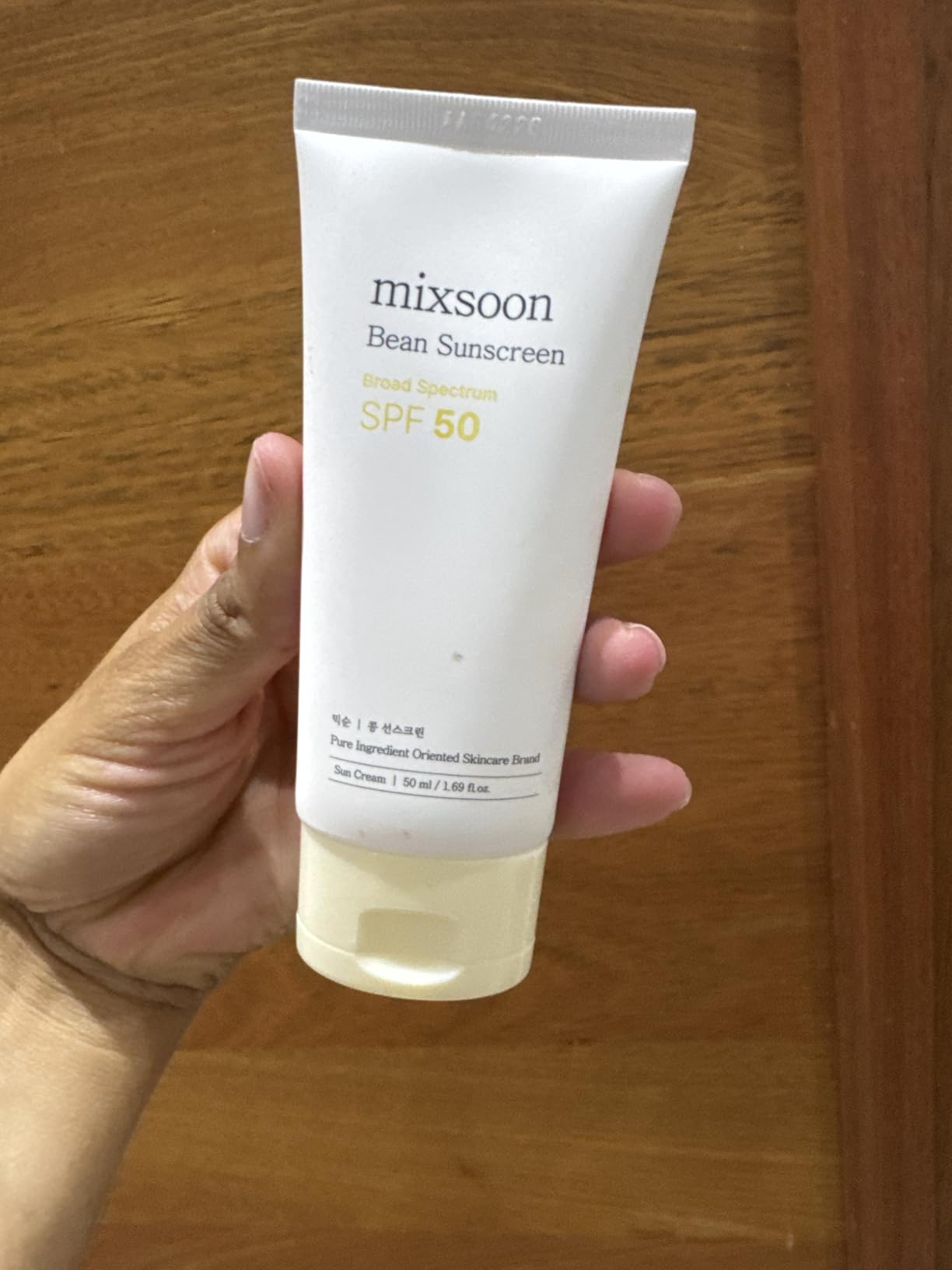 A manus  holds a conduit  of Mixsoon Bean Sunscreen SPF 50, labeled arsenic  wide  spectrum with 1.69 fl oz
