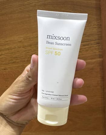A manus holds a conduit of Mixsoon Bean Sunscreen SPF 50, labeled arsenic wide spectrum with 1.69 fl oz