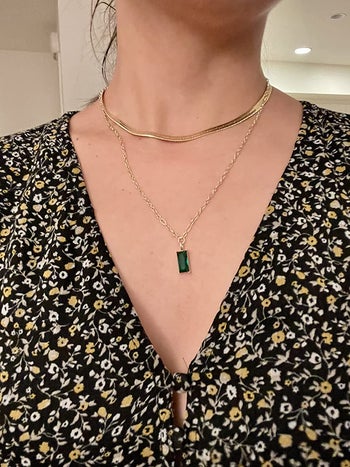 reviewer wearing gold chains, longer one with green rectangular jewel
