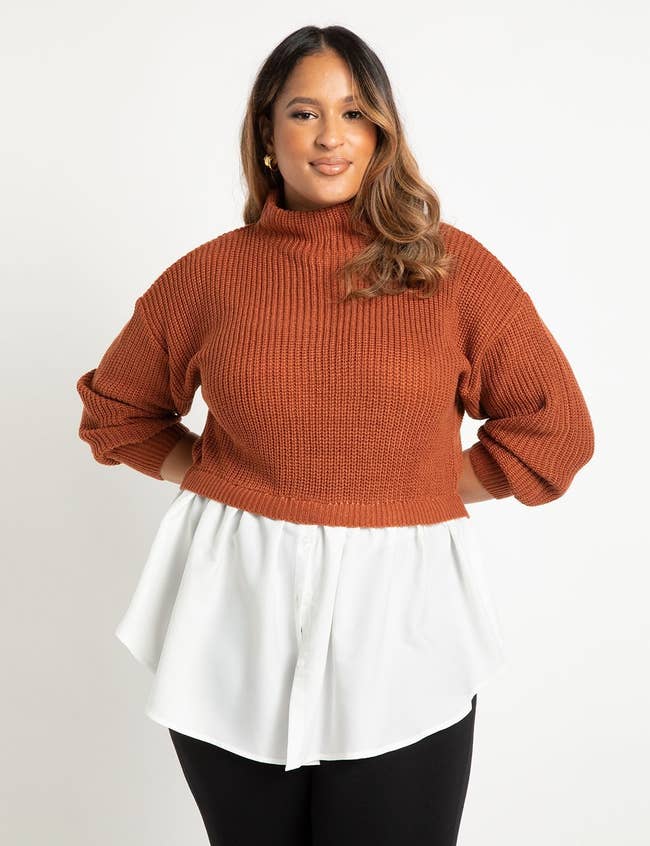 model in a two part sweater that's orange knit on top with a white button down part sticking out of the bottom