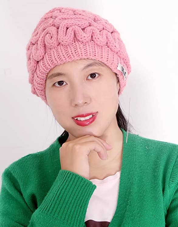 Model wearing pink brain shaped beanie with a green cardigan and white shirt