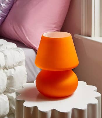 Small orange lamp on a white ridged side table, contemporary design, for interior decor