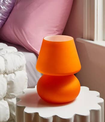 Small orange lamp on a white ridged side table, contemporary design, for interior decor