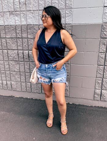 A reviewer wearing distressed denim blue shorts