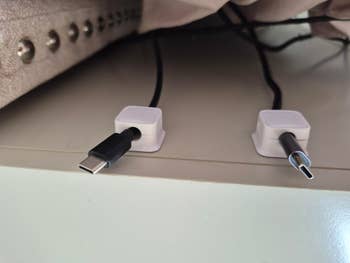 Two magnetic cablegram  organizers with USB-C cables attached connected  a table  edge, showcasing a neat solution   for cablegram  management