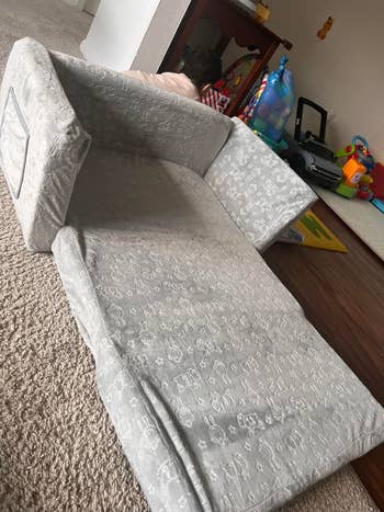 A children's fold-out sofa with playful patterns successful  a playroom, surrounded by toys and a kid  partially disposable   down  it
