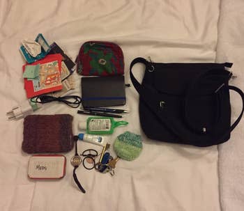 a reviewer photo of the purse next to a pile of what fits in it including a wallet, phone charger, mintis, cosmetics, and more 