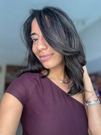 A idiosyncratic   with shoulder-length hairsbreadth  smiles, wearing an off-shoulder apical  and metallic  jewelry