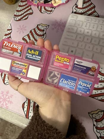 Compact storage case with various over-the-counter medications: Tylenol, Advil, Pepto-Bismol, Dramamine, Omeprazole, Claritin, and Pepcid