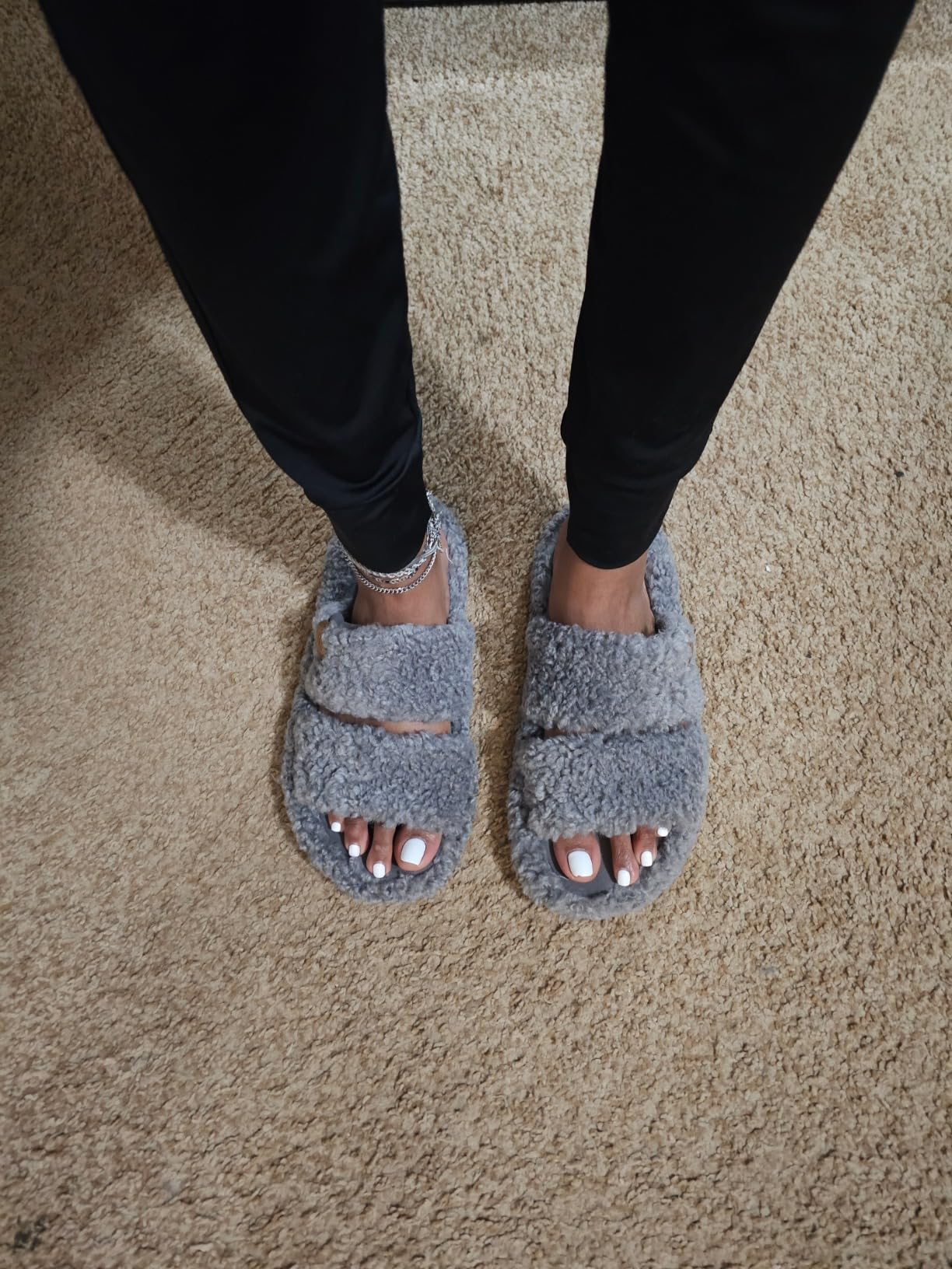 Fuzzy, open-toed slippers connected  a carpet worn by a idiosyncratic   with a metallic  anklet, showcasing casual, cozy footwear cleanable   for location  lounging