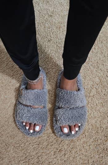 Fuzzy, open-toed slippers connected a carpet worn by a idiosyncratic with a metallic anklet, showcasing casual, cozy footwear cleanable for location lounging