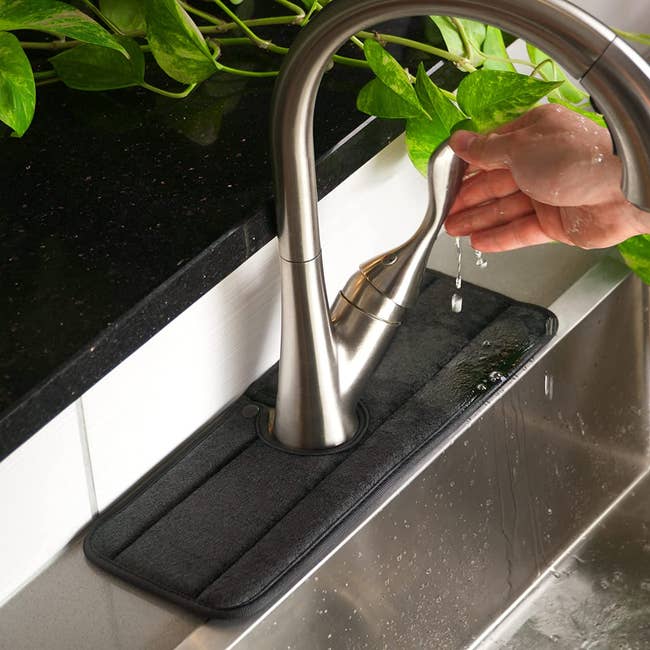 a black fabric splash guard fitted around a sink's faucet