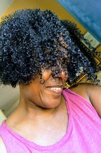 Person with curly hairsbreadth smiling, wearing a casual sleeveless top