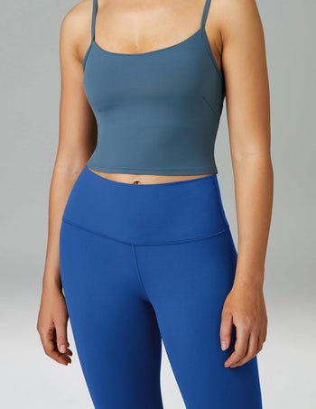 Model in a crop top and blue high-waisted leggings