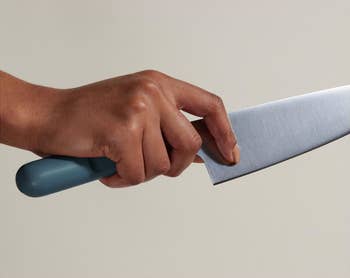 hand holding the blue handled knife