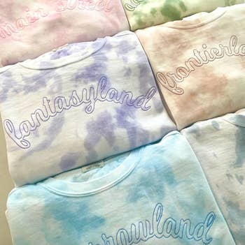 an array of pastel colored tie dyed sweatshirts with names of disney locations embroidered on each one