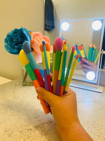 image of reviewer's hand holding the set of makeup brushes