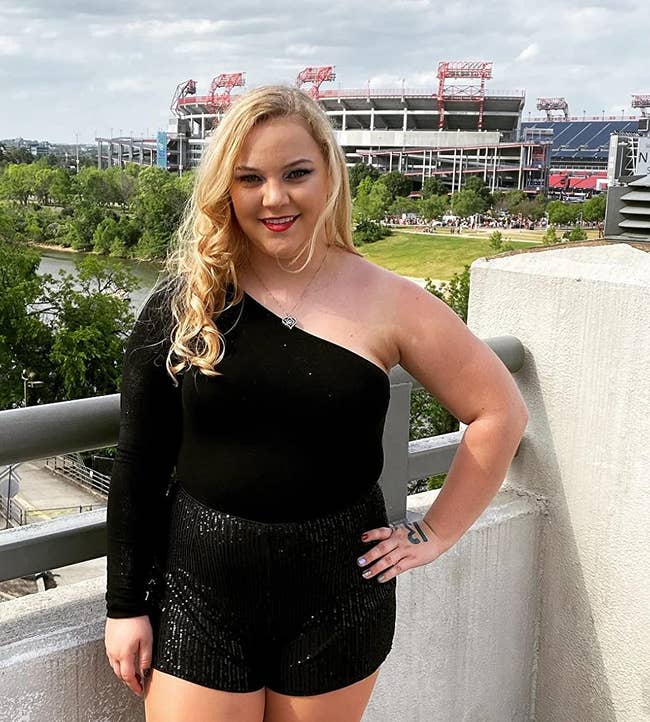 Reviewer posing in a black top and sequined shorts with a stadium in the background