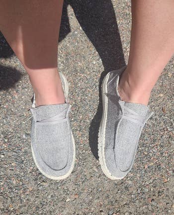 Person wearing gray slip-on shoes with white soles 