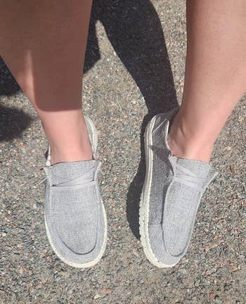 Person wearing gray slip-on shoes with white soles 
