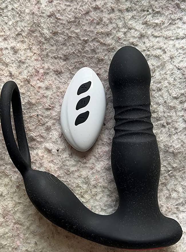 Black prostate vibrator next to white wireless remote