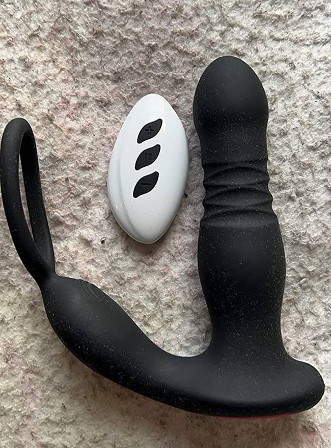 Black prostate vibrator next to white wireless remote