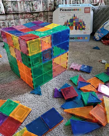 Reviewer using tiles to form a cube with extra tiles in front and the box they came in in the background