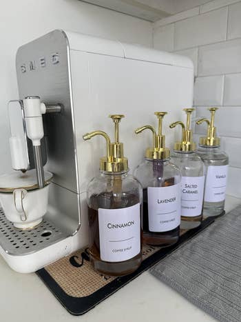 Coffee instrumentality   beside cinnamon, lavender, salted caramel, and vanilla syrup bottles connected  a room  counter