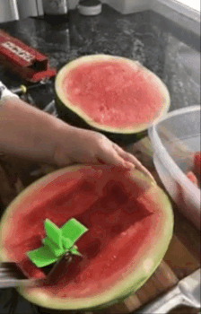 gif of reviewer using the cutter to easily cut up half a watermelon