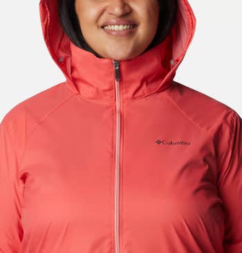 Person smiling in a red Columbia hooded rain jacket with zipper closure