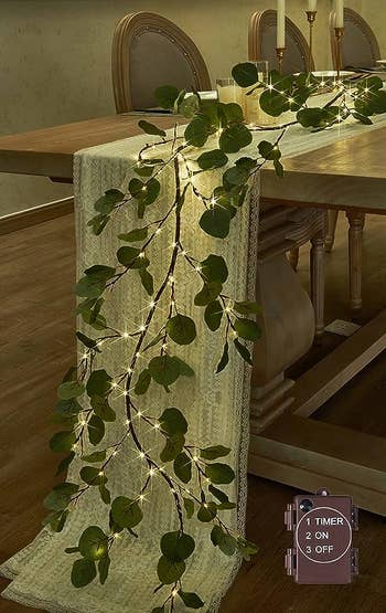 a lighted faux eucalyptus garland on a table
