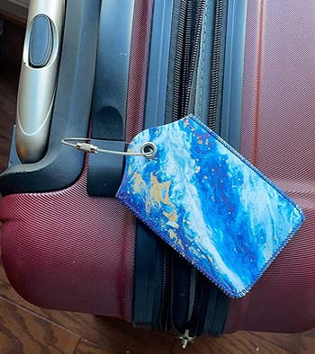 reviewer photo of the blue wave luggage tag attached to a suitcase