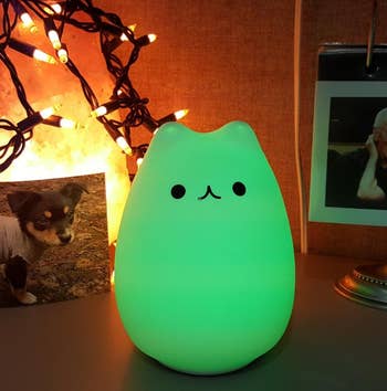 a reviewer photo of the cat-shaped lamp illuminated green 