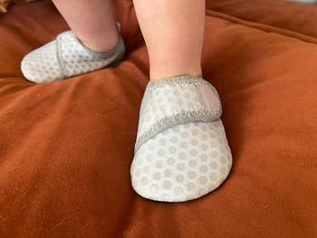 A reviewer's baby wearing white soft-soled shoes with polka dot design