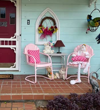 two pink metal chairs with a tulip design on the back sitting on a porch 