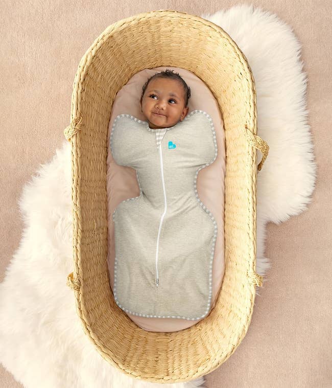 Baby successful a fitted swaddle sleepsuit successful a woven basket, lying connected a brushed surface