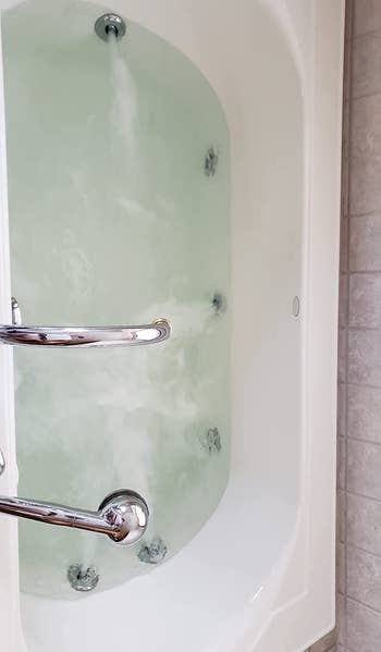 reviewer after photo of the tub filled with perfectly clear water after being cleaned