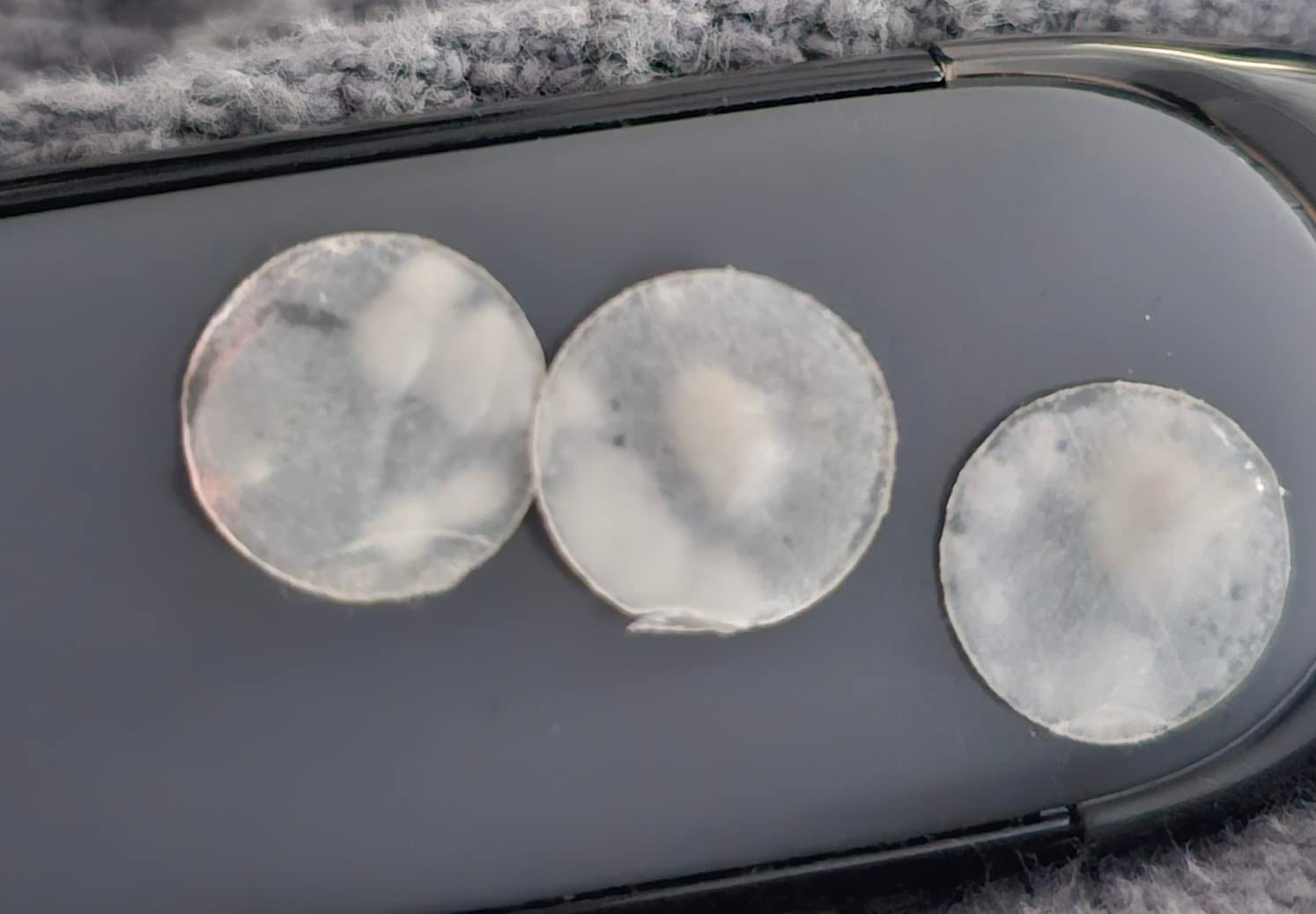 Three clear, utilized  circular  acne patches connected  a telephone  case