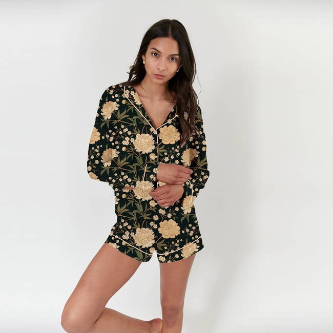 a model in. black silk pajamas with yellow flowers on them