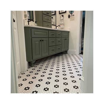 Bathroom with green cabinets, dual sinks, and hexagonal tile flooring showcasing a floral pattern