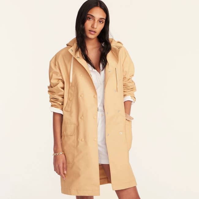model wearing a sandy colored double breasted raincoat