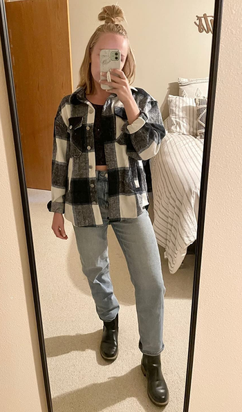 a reviewer wearing the plaid shaket in white and navy blue over a crop top and jeans 
