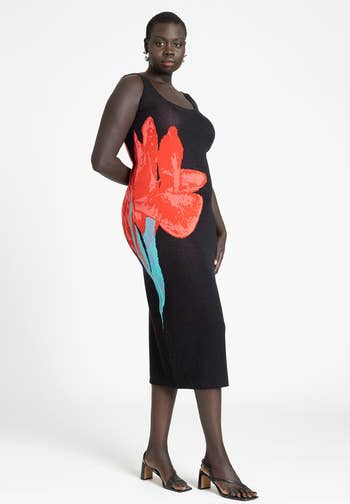 Model in a fitted black dress with a large red flower design