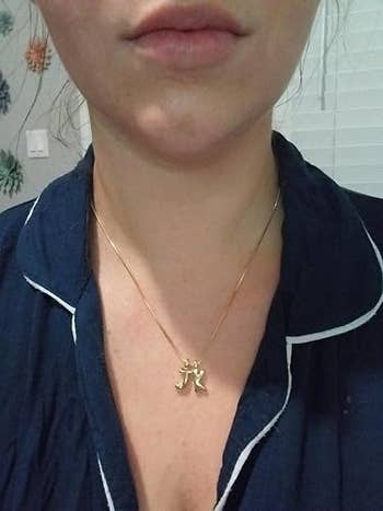 Person wearing a necklace with a golden  pendant featuring a stylized design, dressed successful  a casual outfit with white-trimmed details