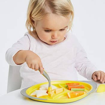 A child using the fork to pick p food