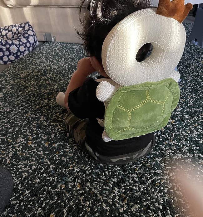 image of reviewer's child wearing the tortoise-shaped cushion backpack