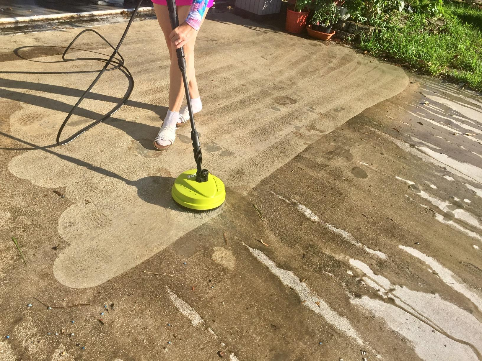 Person pressure washing a concrete patio