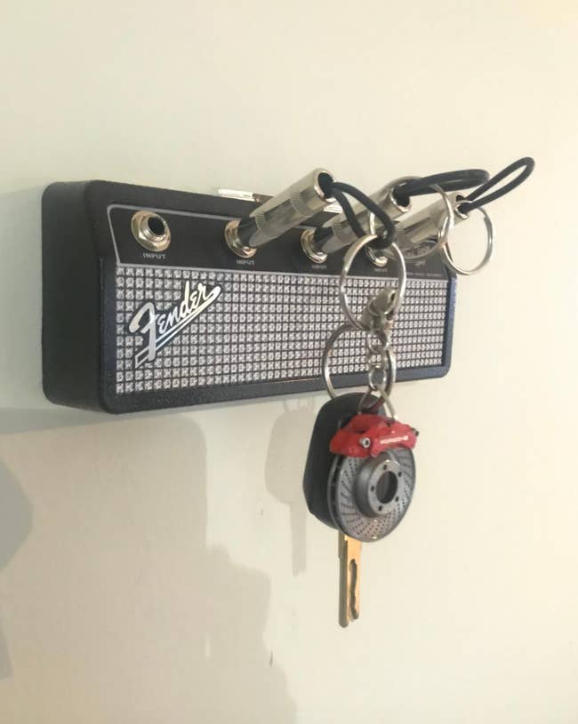 A key holder installed to a wall that mimics a Fender guitar amp plug 